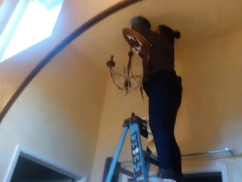 Electrician installing a chandelier in a Northbridge residence